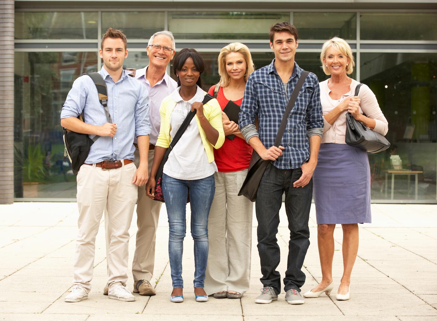 A smiling group of adult students standing together outdoors on a campus